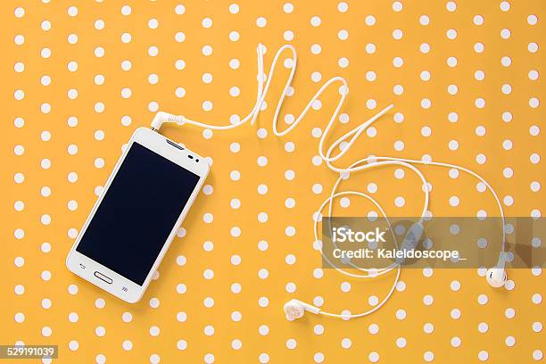 Small Headphones With Mobile Phone On Yellow Vintage Paper With Stock Photo - Download Image Now