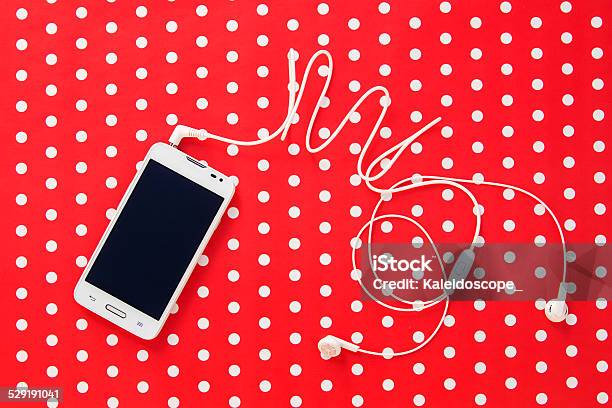 Small Headphones With Mobile Phone On Red Paper With Dots Stock Photo - Download Image Now