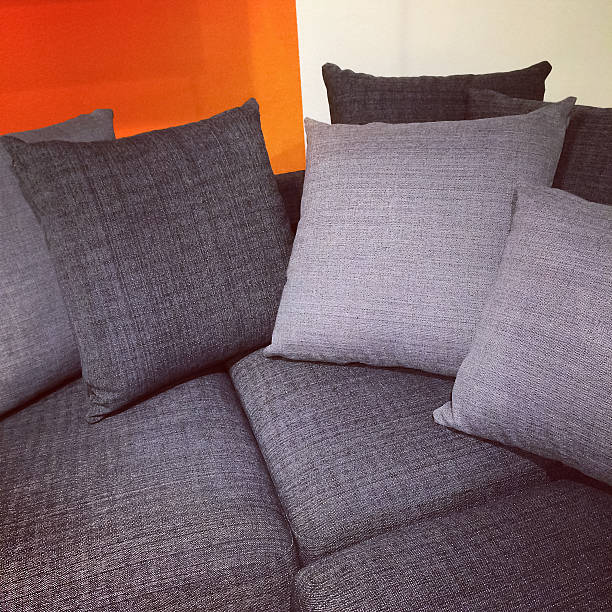 Close-up of modern gray sofa with lots of cushions.