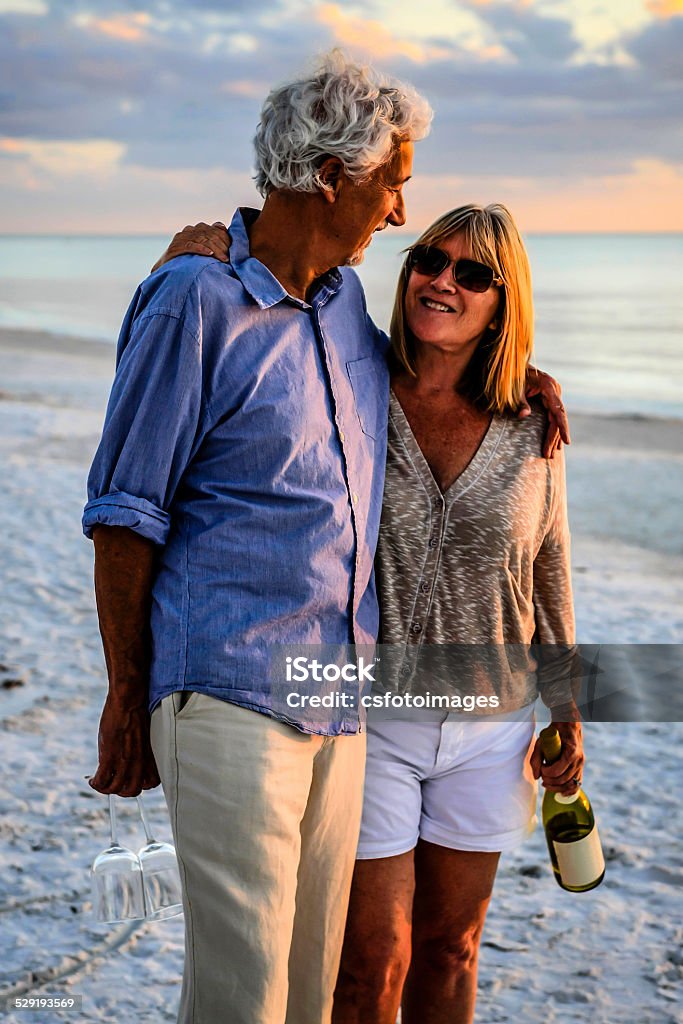 Active retirees enjoy the sunset on Siesta Key beach FL Siesta Key, FL, USA - December 1, 2012: Retired couple enjoy a romantic interlude with a bottle of wine and two glasses at sunset on Siesta Key beach Florida Active Lifestyle Stock Photo