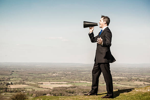 istock Businessman with loudhailer megaphone on hill 529194971