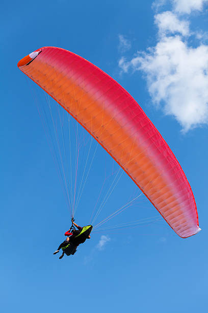 istock Red paraglider in the blue sky with clouds 529207355