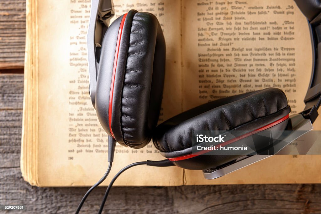 Audiobook concept Headphones on the old book. Concept of listening to audiobooks. Book Stock Photo