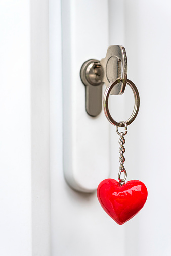 Key inserted into a door lock with a key ring in a heart shape - brightly lit