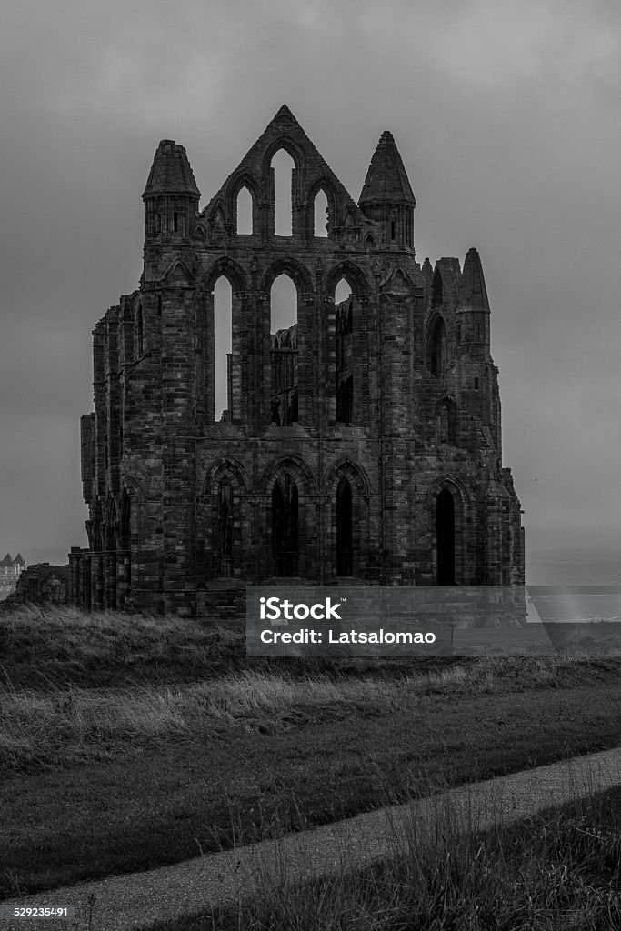 Whitby Abbey rainy view Whitby Abbey is a ruined Benedictine abbey overlooking the North Sea on the East Cliff above Whitby in North Yorkshire. It was disestablished during the Dissolution of the Monasteries under the auspices of Henry VIII. Abbey - Monastery Stock Photo