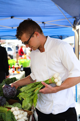 Handsome young chef shops for fresh ingredients at local Farmer's Market.
