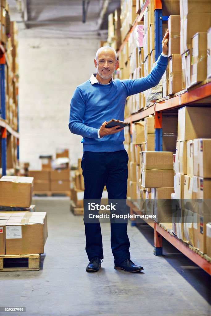 He's in charge A man standing next to industrial shelving with boxes Adult Stock Photo