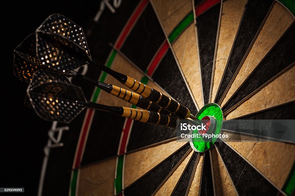 Three darts in bull's eye close up Success hitting target aim goal achievement concept background - three darts in bull's eye close up Darts Stock Photo