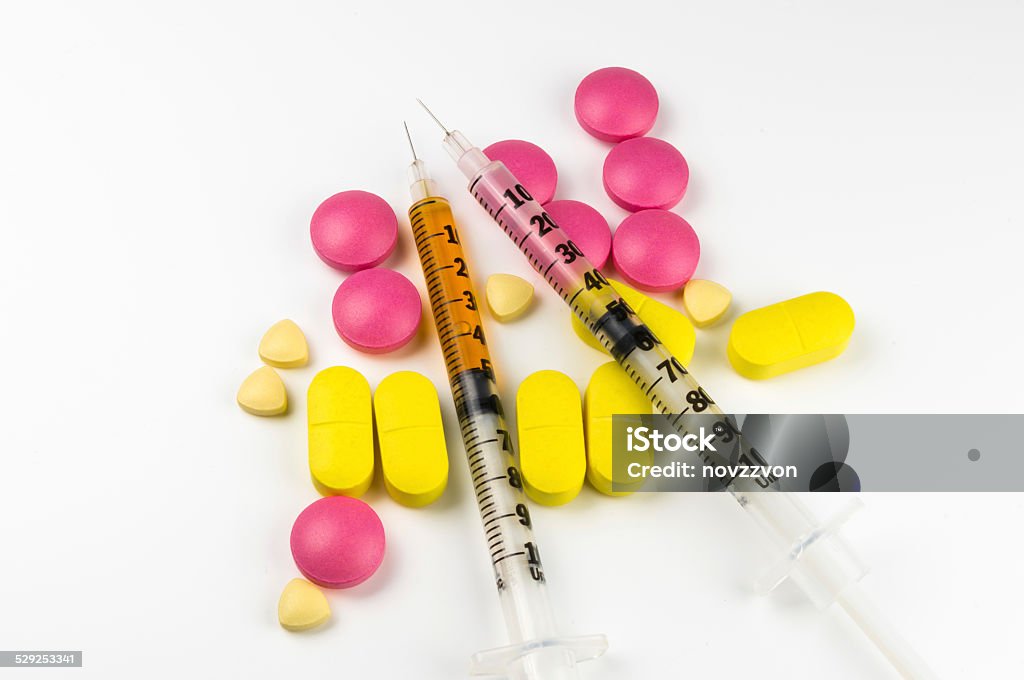 Insulin needles on pills and tablets Insulin needles mixed with some pink tablets Addiction Stock Photo