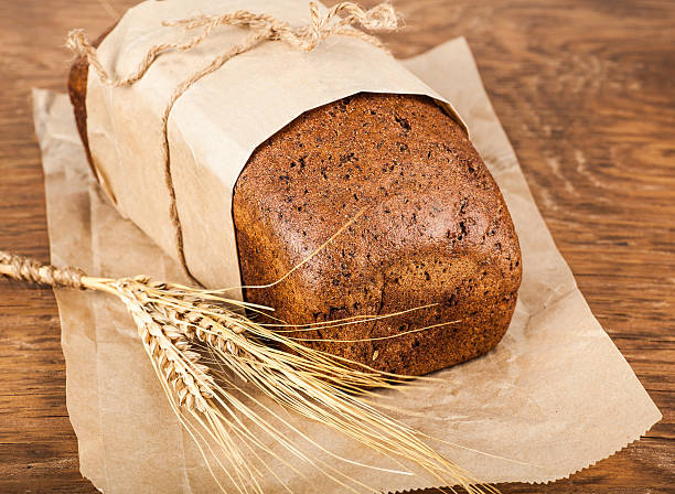 istock bread in a paper packing with ears of wheat 529272439