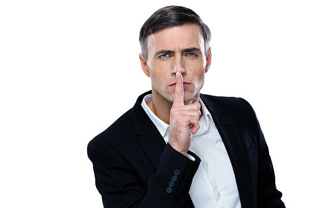 Businessman placing finger on lips saying shhh