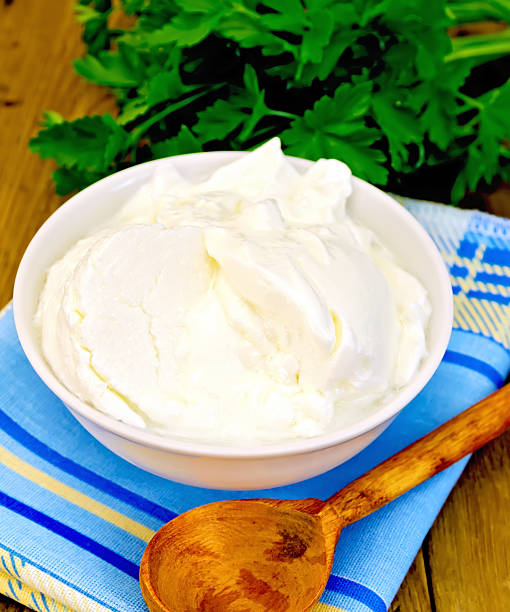 istock Yogurt in white bowl with greens on board 529312135