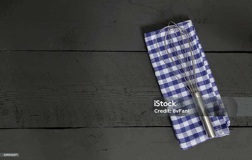 Whisk and tea towel on black wooden background Whisk and tea towel on black wooden background. Anthracite Coal Stock Photo