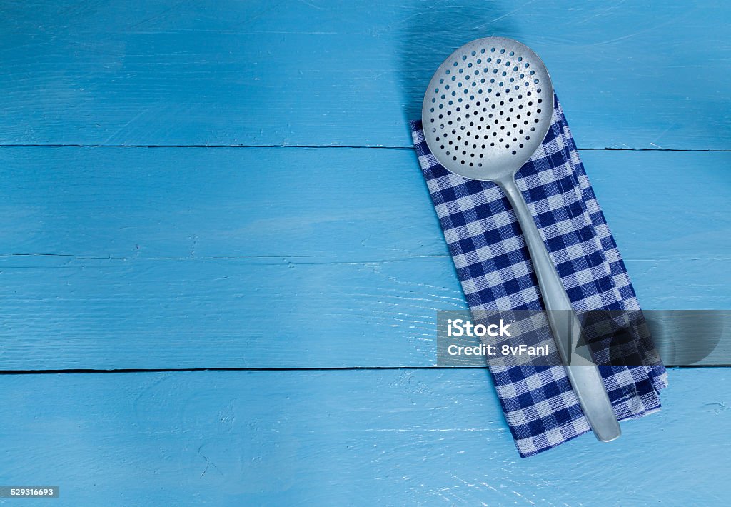 slotted spoon and tea towel on blue wooden background slotted spoon and tea towel on blue wooden background. Bed and Breakfast Stock Photo
