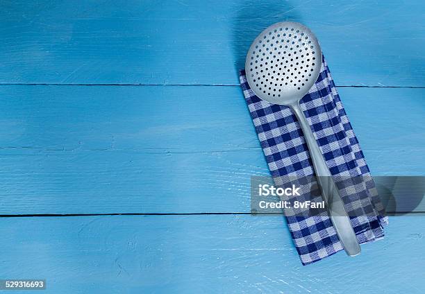Slotted Spoon And Tea Towel On Blue Wooden Background Stock Photo - Download Image Now