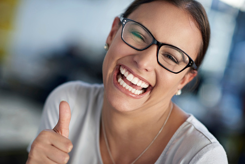 Cropped portrait of a young woman smiling and giving you the thumbs up sign