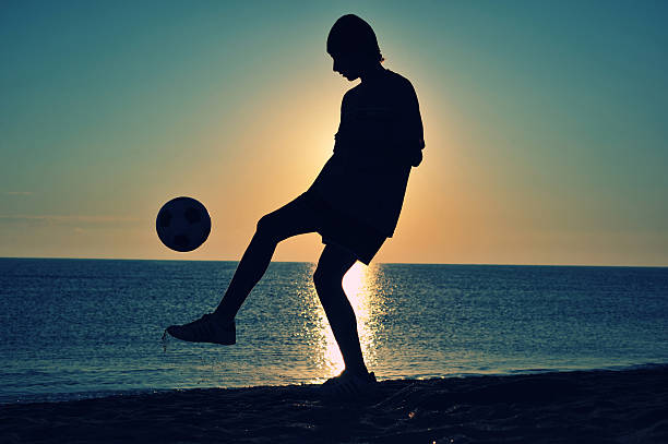 istock Boy playing football on beach 529352029