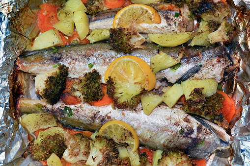 Baked fresh fish and vegetables in casserole with foil.