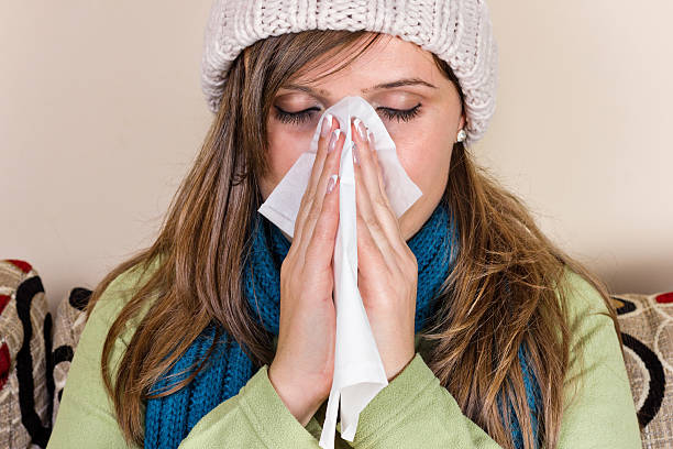 istock Young woman blowing her nose into tissue 529354003