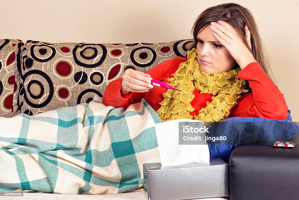 Young woman having flu and taking her temperature Young woman having flu and taking her temperature at home Adult Stock Photo