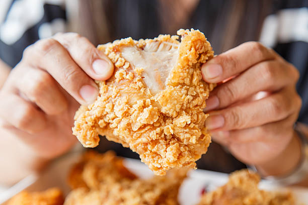 mano con pollo fritto e mangiare nel ristorante - croccante foto e immagini stock