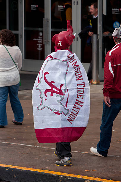 Alabama Fan In Caped Costume Walks Toward Georgia Dome Atlanta, GA, USA - December 6, 2014:  A confident University of Alabama fan dressed in a cape and elephant hat, walks toward the Georgia Dome to watch the SEC Championship game against Missouri. georgia football stock pictures, royalty-free photos & images