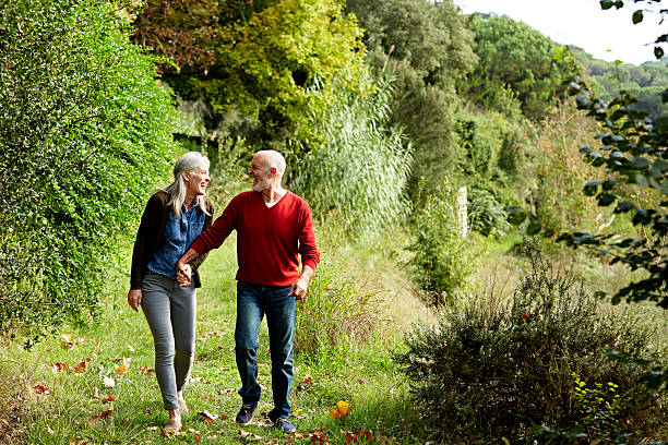 happy senior couple walking in park - holding hands couple senior couple togetherness foto e immagini stock