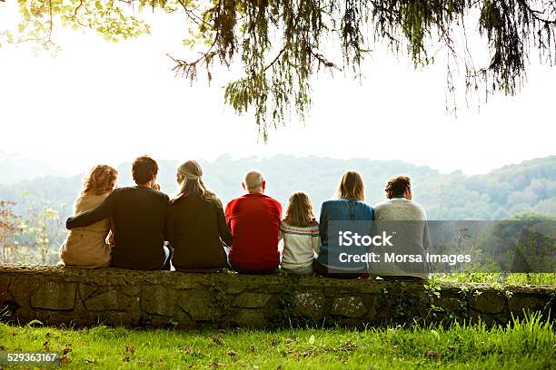 Multigeneration Family Relaxing On Retaining Wall Stock Photo - Download Image Now - Multi-Generation Family, Rear View, Senior Adult