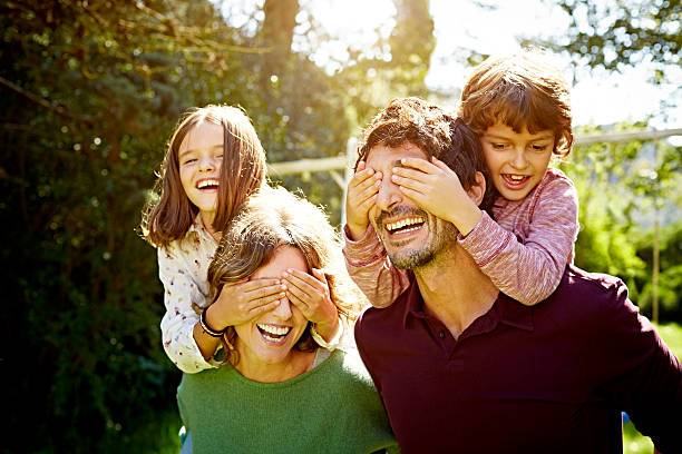 children enjoying piggyback ride on parents - couple fun outdoors day 뉴스 사진 이미지