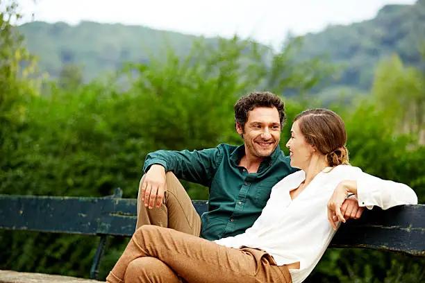 Photo of Happy couple sitting on park bench