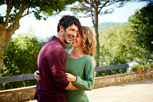 cheerful couple embracing in park - parejas fotografías e imágenes de stock
