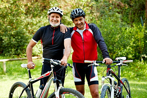 Portrait of happy father and son with bicycles in park