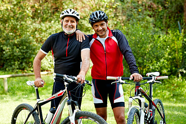 father and son with bicycles in park - cycling senior adult sports helmet men zdjęcia i obrazy z banku zdjęć