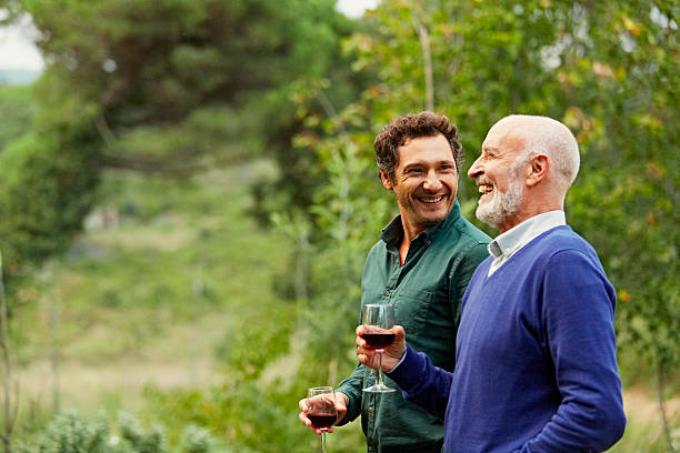 father and son having red wine in park - sohn stock-fotos und bilder