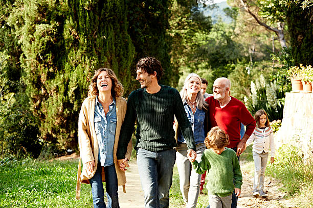 happy family walking in park - senior adult child holding grandparent photos et images de collection