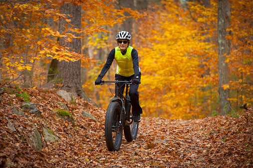 Attractive woman riding a fatbike on a leaf covered trail