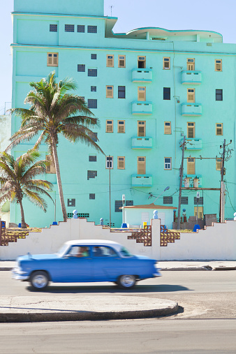 Subject: Classic old cars speeding down the sea wall the Malecón along the old Havana in Cuba.