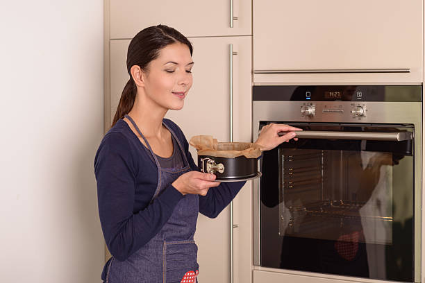 istock Young woman placing a cake in the oven 529384661