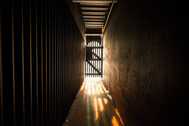 corredor escuro com luz no fim do túnel - lock door horror gate imagens e fotografias de stock