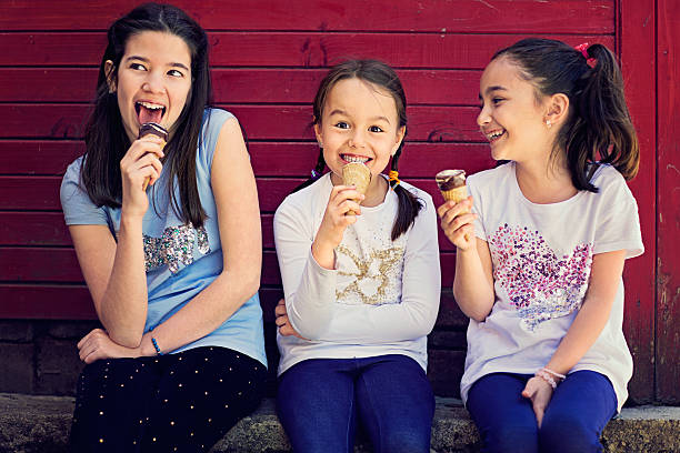 Childhood Three girls are very happy and eating ice cream. One of them trying to steal some ice cream from her little sister. stealing ice cream stock pictures, royalty-free photos & images