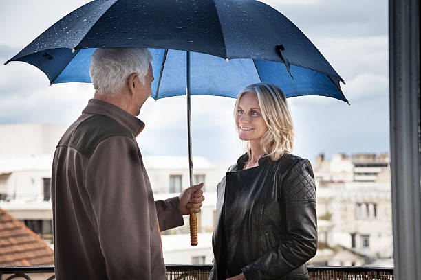 couple d'âge mûr brave la pluie sur le balcon de l'appartement à paris - rain women umbrella parasol photos et images de collection