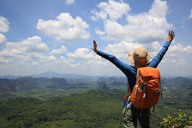 istock cheering successful woman hiker open arms at mountain peak 529397554