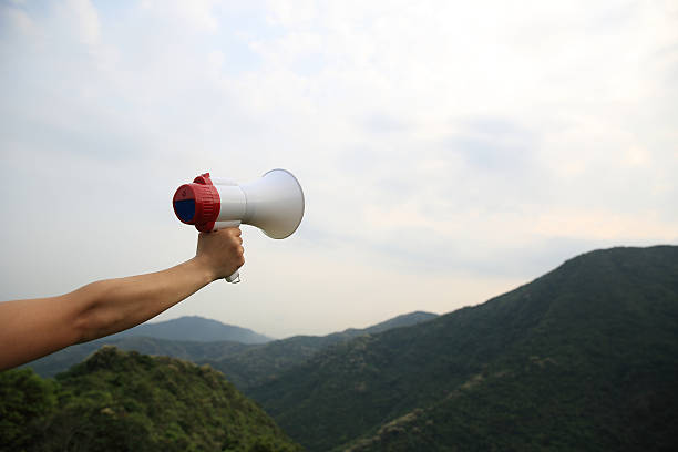 istock hand hold loudspeaker to blue sky on mountain peak 529399458