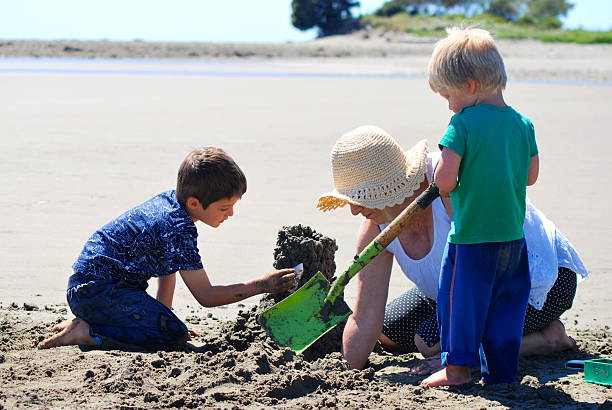 abuela y nietos construir castillos de arena en la - golden bay fotografías e imágenes de stock