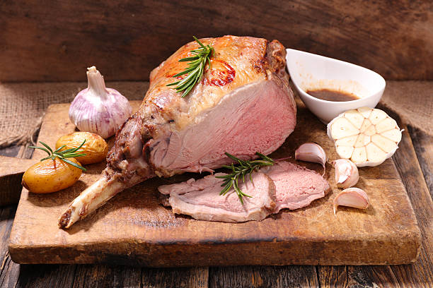 roasted lamb leg on board roasted lamb leg with potato,garlic and sauce lamb meat photos stock pictures, royalty-free photos & images