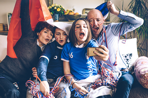 french family soccer fans watching soccer game on smartphone
