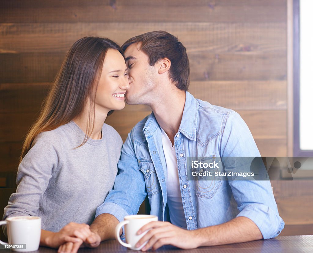 Showering her with affection Cropped shot of a handsome young man kissing his girlfriend in a coffee shop Adult Stock Photo