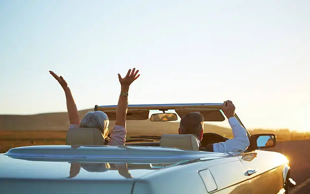 Rear view shot of a happy couple in a car excited about the sun rise