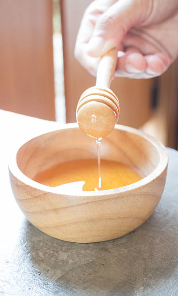istock Hand on honey dipper from wooden cup 529409626