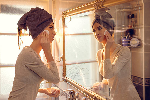 jeune femme nettoyage son visage dans la salle de bains. - applying make up flash photos et images de collection